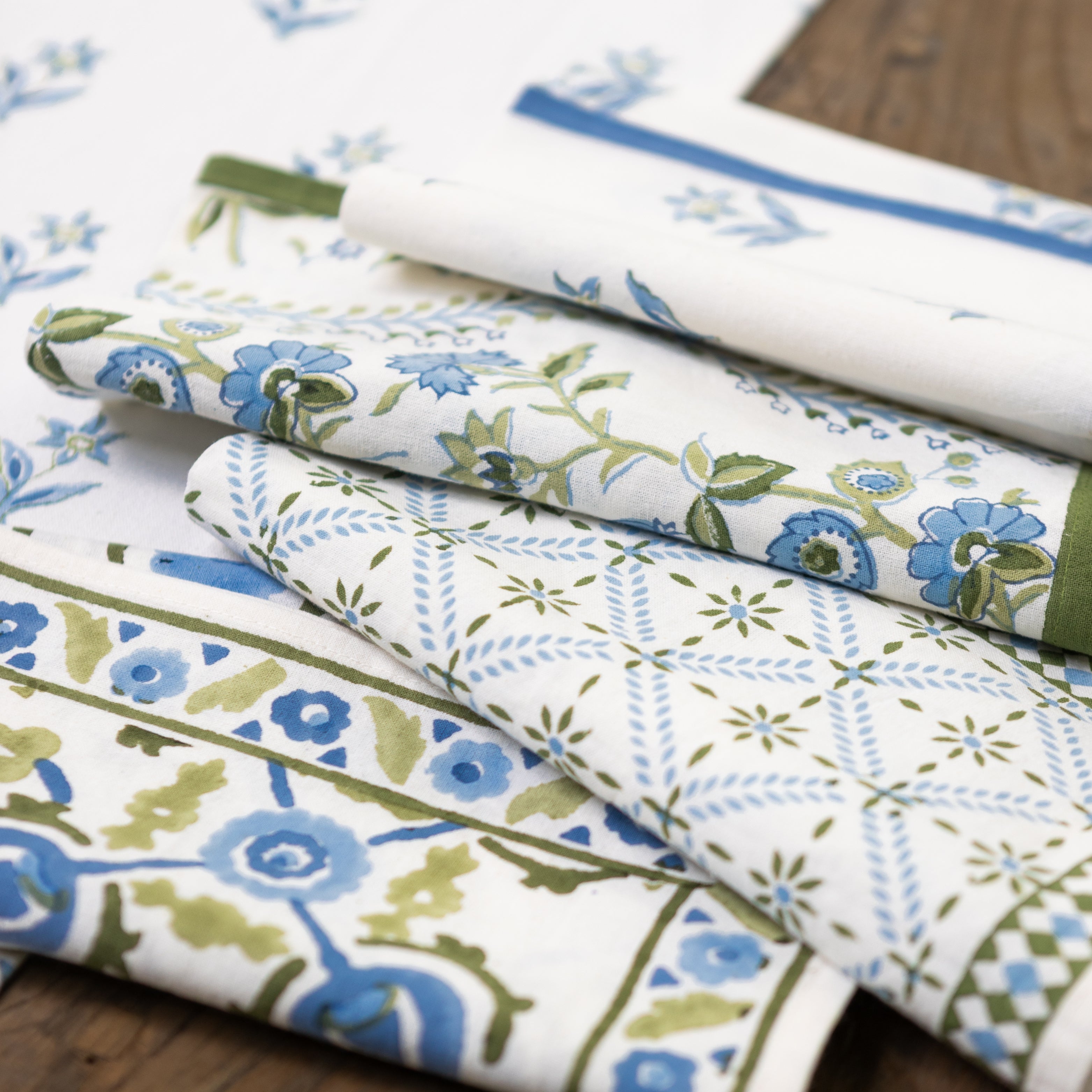 Stack of floral and geometric patterned fabric swatches on a wooden surface