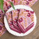 Set of pink floral patterned napkins on a white plate with a matching pink tablecloth.