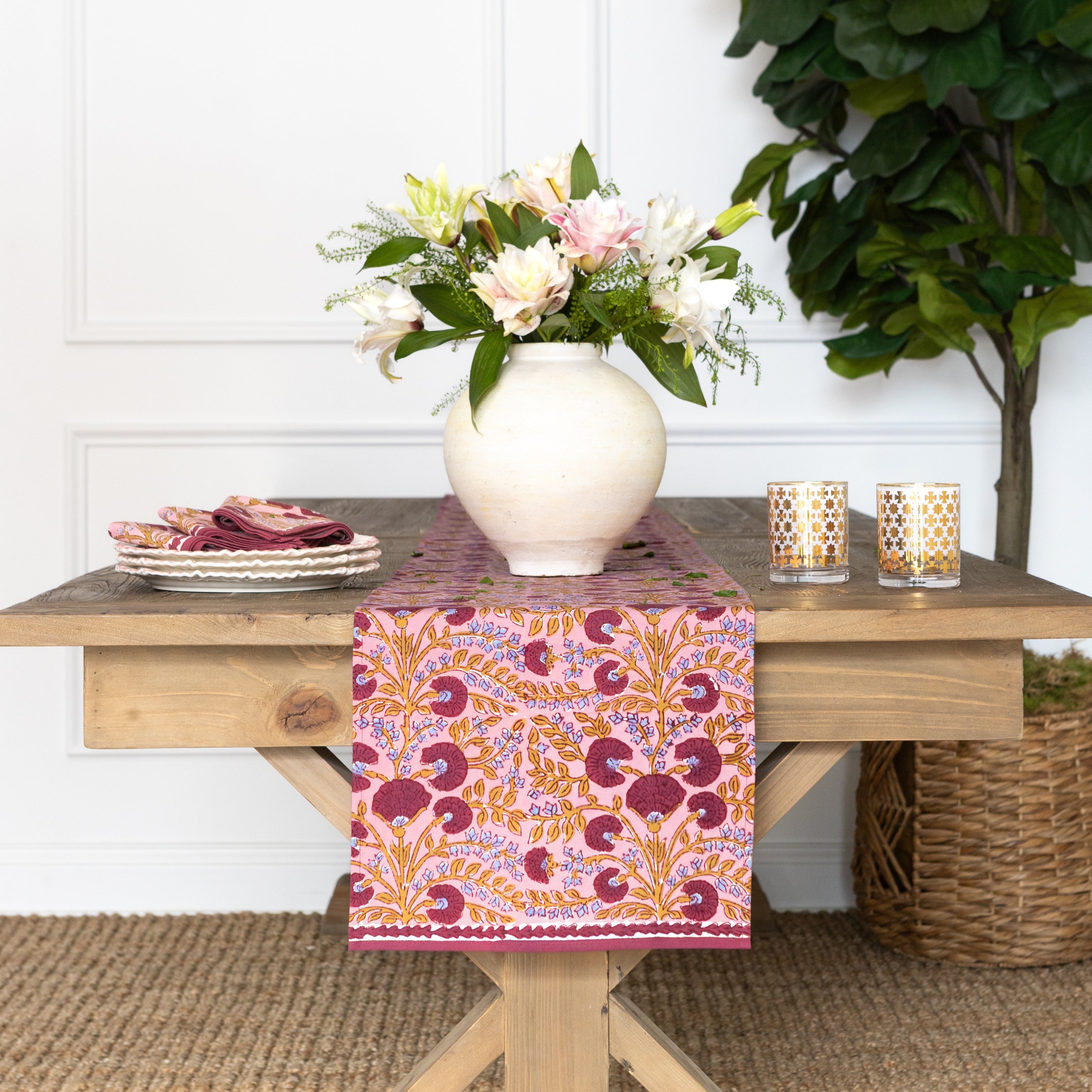 Table setting with a floral arrangement, candles, and a patterned table runner.