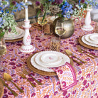 Decorative table setting with floral centerpieces, patterned tablecloth, and gold cutlery.