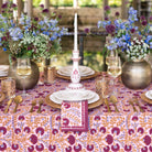 Elegant table setting with floral centerpieces, candles, and patterned tablecloth.
