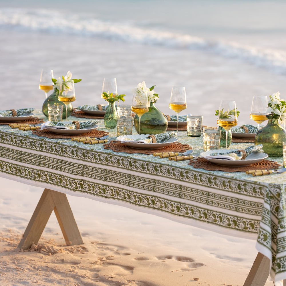 Caroline Green Tablecloth on an outdoor dinner table with wine, flowers, and food.