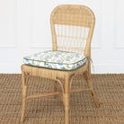 Wicker chair with a floral cushion on a textured floor.