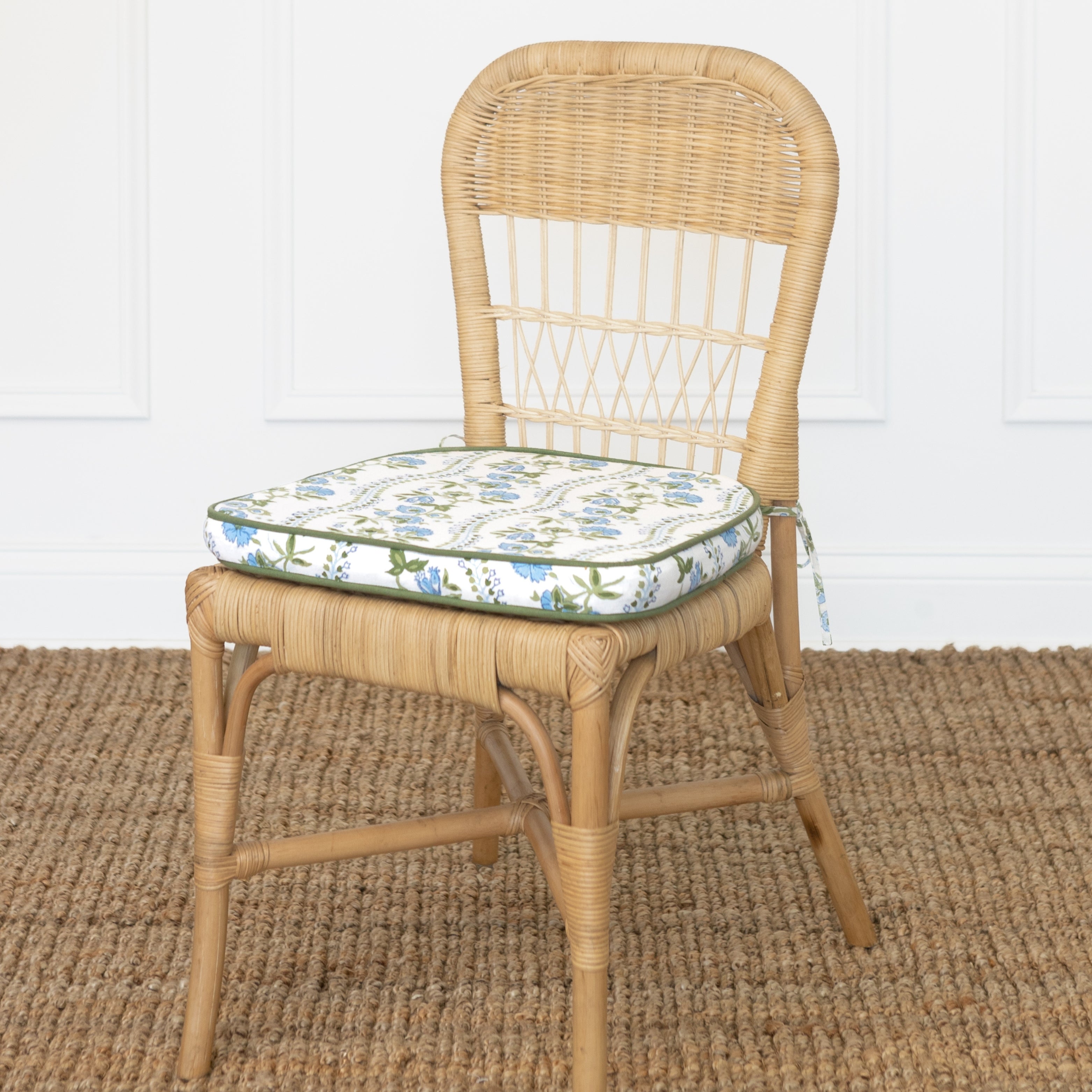 Wicker chair with a floral cushion on a textured floor.