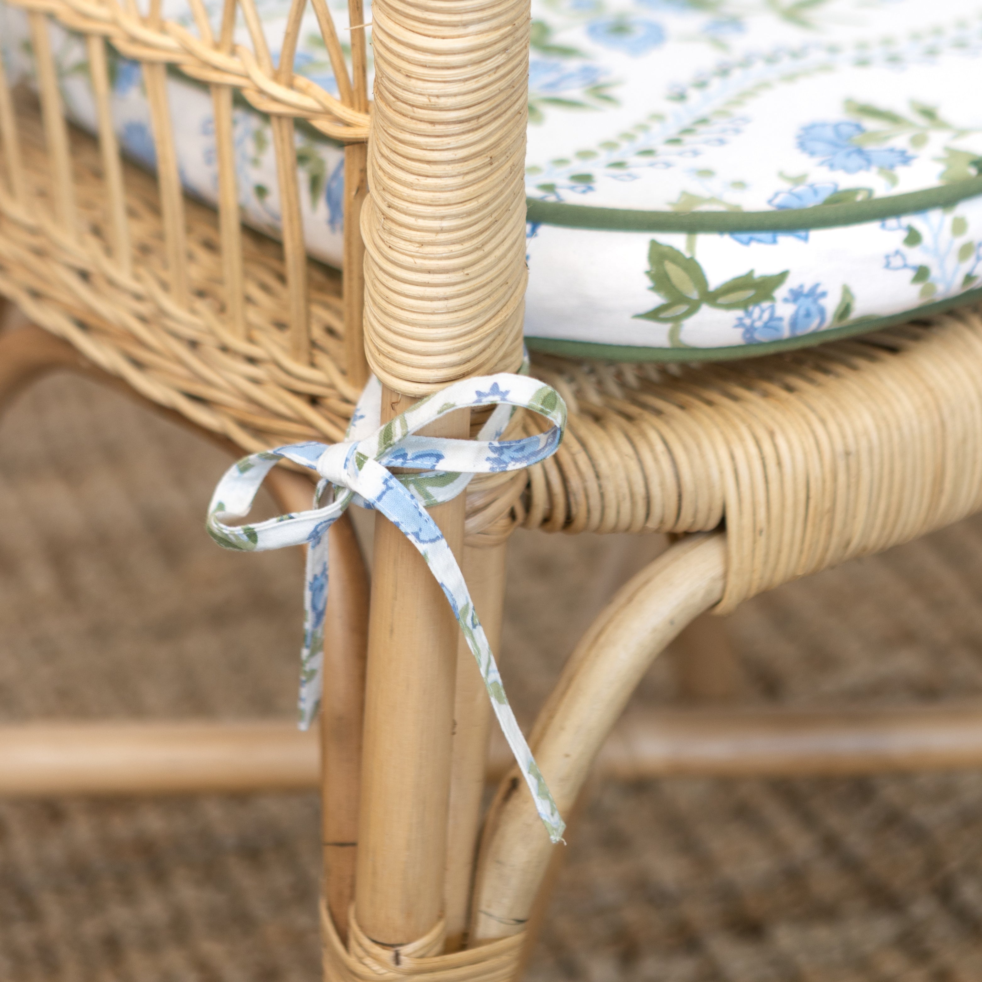 Wicker chair with floral cushion and ribbon tie, blurred background