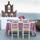 A set dining table with the Climbing Dahlia Lilac Tablecloth featuring a floral design, placed outdoors with a scenic background.