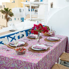 A set dining table with the Climbing Dahlia Lilac Tablecloth featuring a floral design, placed outdoors with a scenic background.