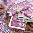 Lilac floral napkins stacked on a woven charger and matching tablecloth