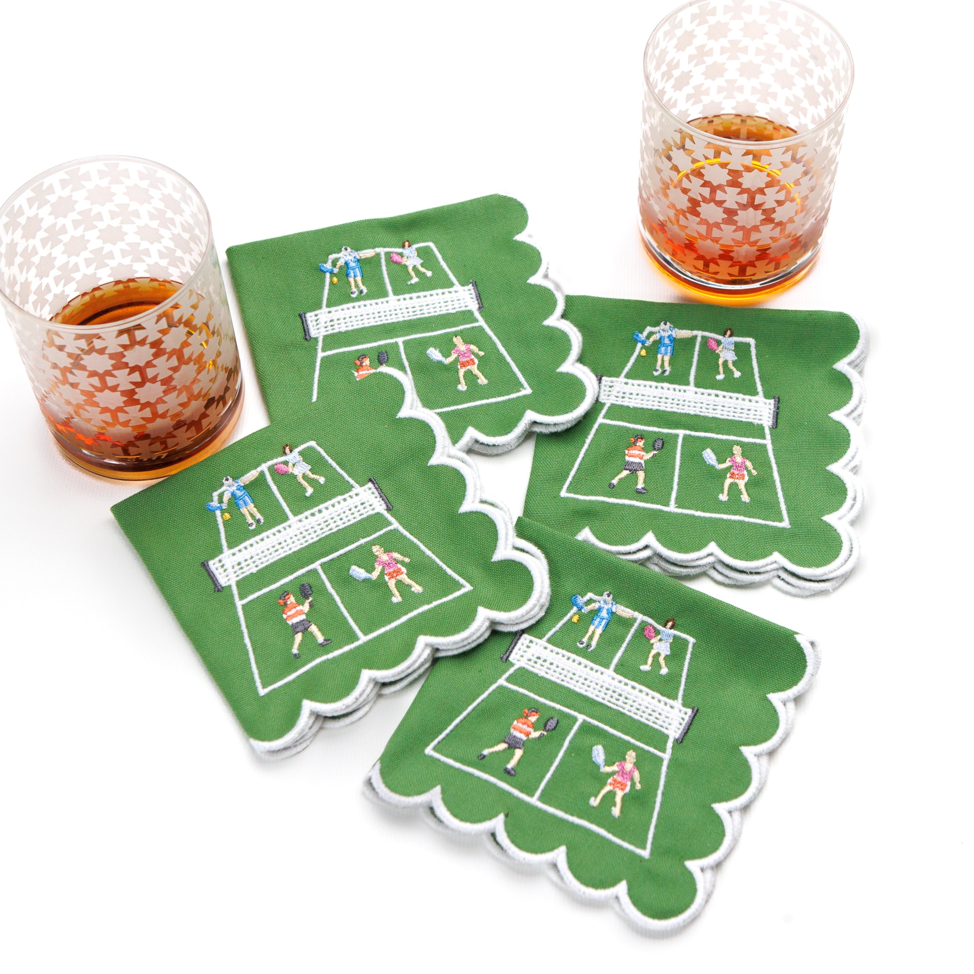 Set of four green cocktail napkins with pickleball design on a white background