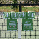 Green towels and cocktail napkins with pickleball design hanging on a tennis net