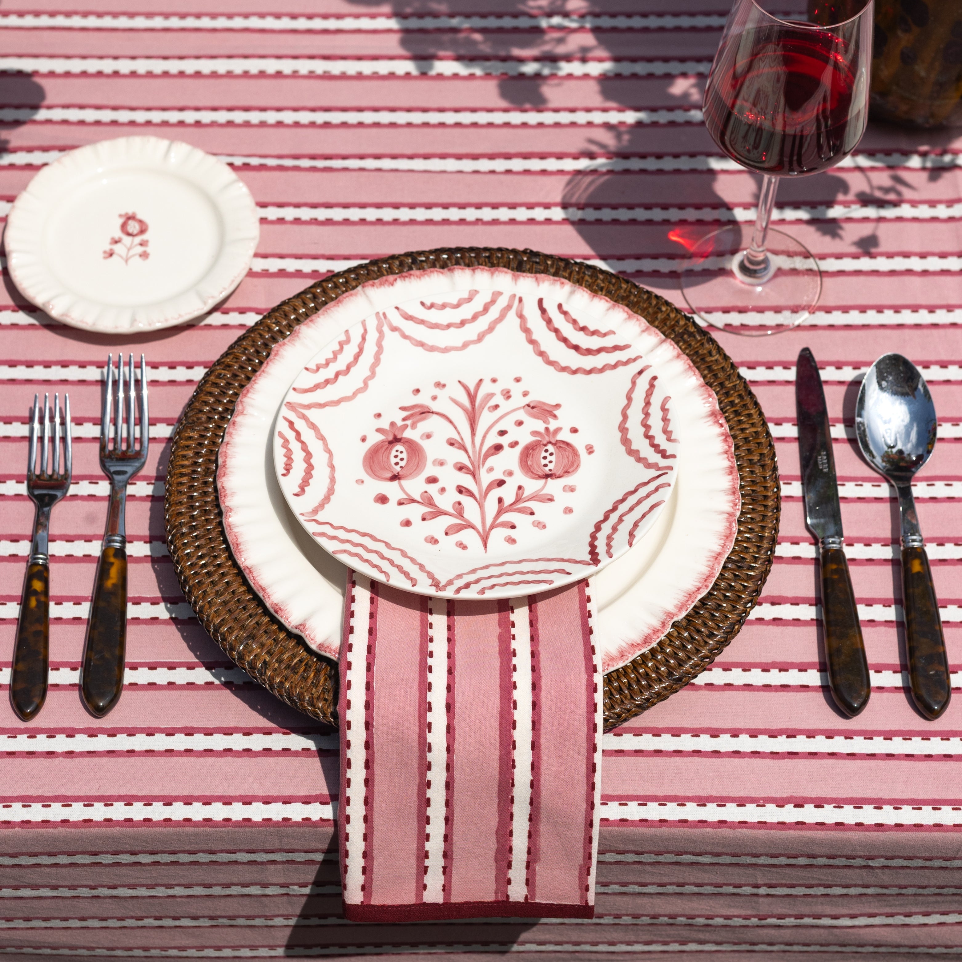 Dining table setting with a decorative plate, cutlery, and striped tablecloth.