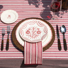 Dining table setting with a decorative plate, cutlery, and striped tablecloth.