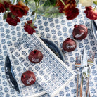 Table setting with personalized red pomegramates on a blue and white patterned tablecloth.