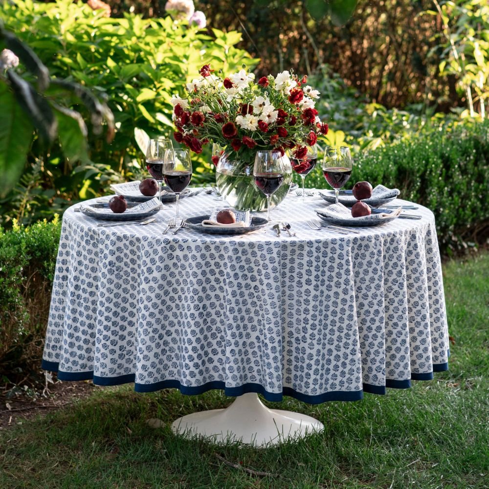 Dining table set with a floral centerpiece, plates, and glasses outdoors.