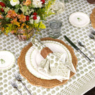 Elegant table setting with floral centerpiece, plates, cutlery, and glasses on a patterned tablecloth.