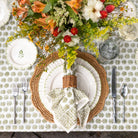 Elegant table setting with floral centerpiece, woven placemat, and patterned tablecloth.