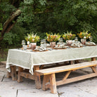 Outdoor table setting with floral centerpieces and tablecloth in a garden.