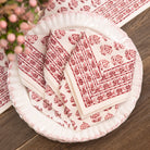 Set of red and white patterned paper plates and napkins on a wooden surface.