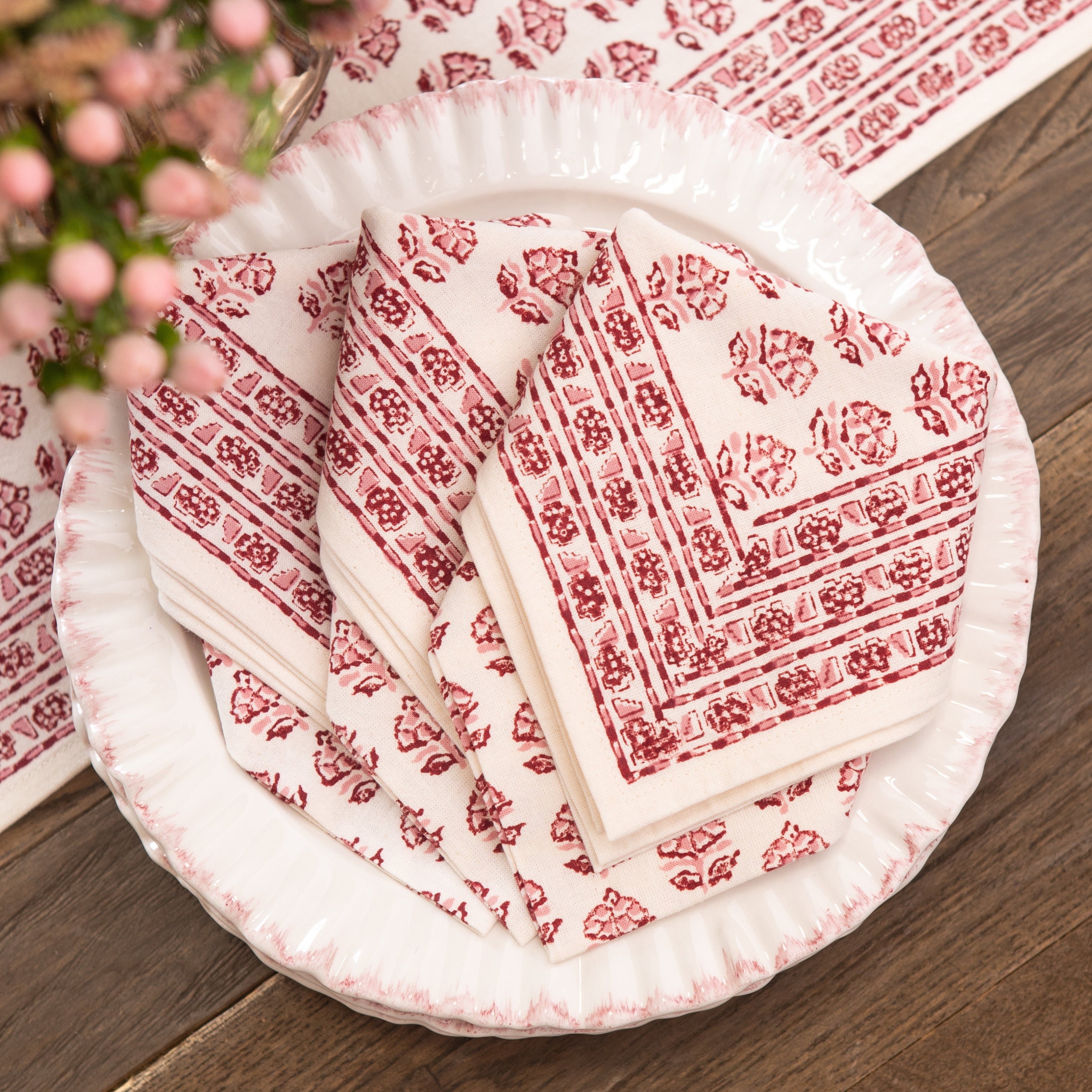 Set of red and white patterned paper plates and napkins on a wooden surface.