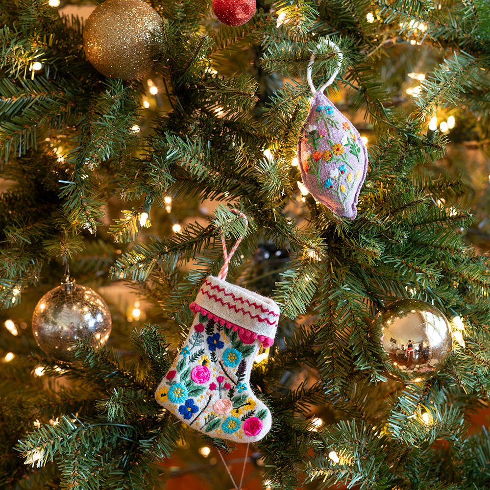 Embroidered ornaments hanging on a lit Christmas tree.