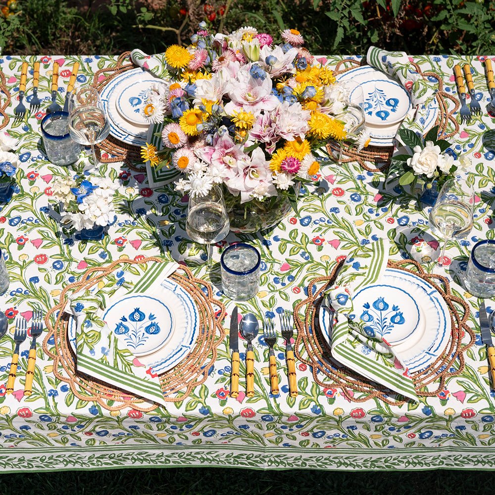 A colorful floral tablecloth with yellow, blue, and red flowers displayed on a table outdoors.