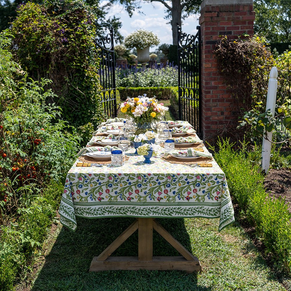 A colorful floral tablecloth with yellow, blue, and red flowers displayed on a table outdoors.