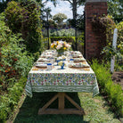 A colorful floral tablecloth with yellow, blue, and red flowers displayed on a table outdoors.