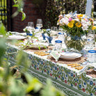 A colorful floral tablecloth with yellow, blue, and red flowers displayed on a table outdoors.