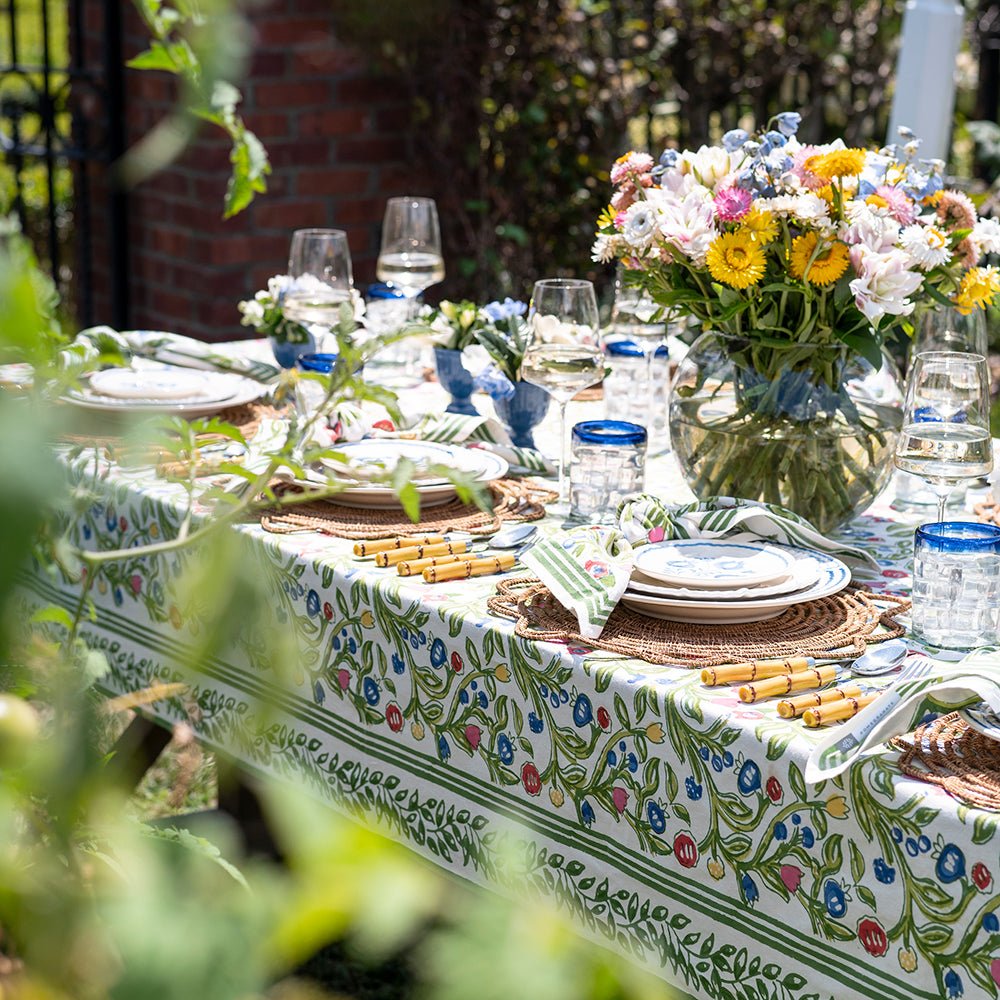 A colorful floral tablecloth with yellow, blue, and red flowers displayed on a table outdoors.