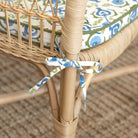 Close-up of a wicker chair with a decorative ribbon and cushion