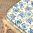 Patterned cushion with blue and green design on a wicker chair