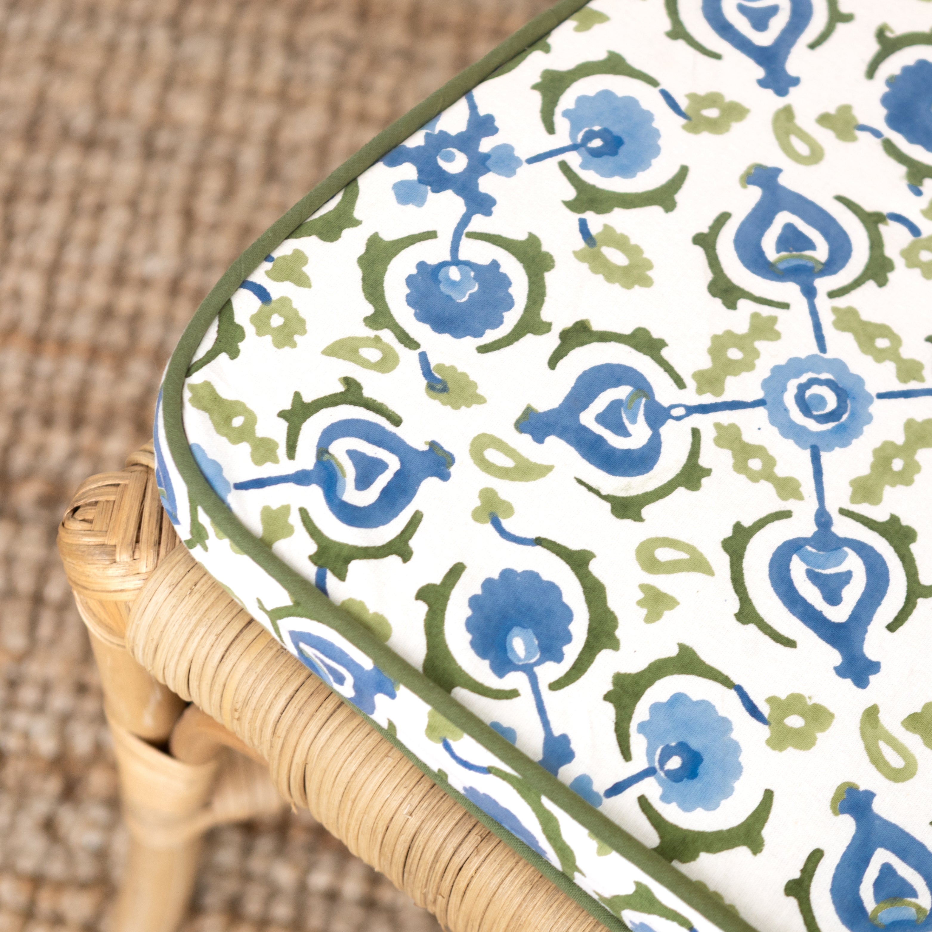 Patterned cushion with blue and green design on a wicker chair