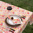 Table setting with floral tablecloth, plates, cutlery, and a glass