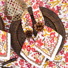 Floral-patterned napkins on a decorative table setting with woven placemats and pinecones.