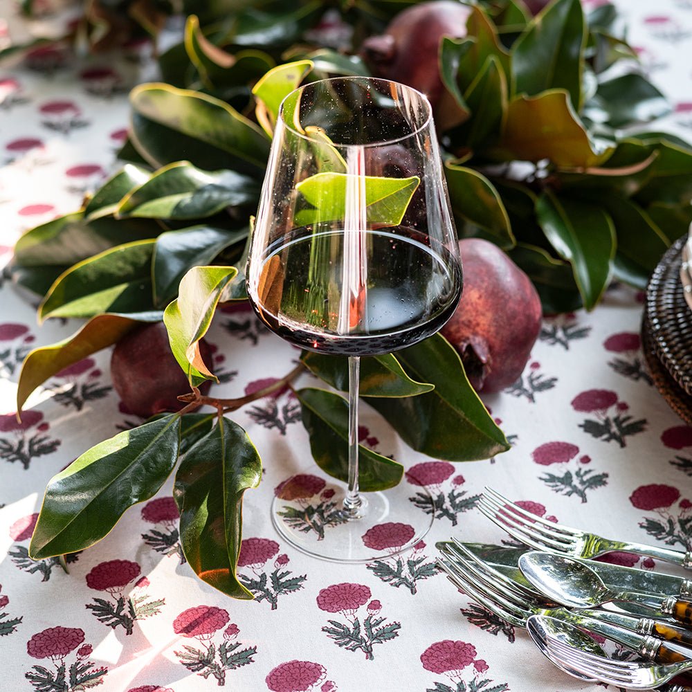 Wine glass with red wine on a tablecloth with fruit and leaves