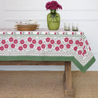 Tablecloth with floral pattern on a wooden table against a white wall.