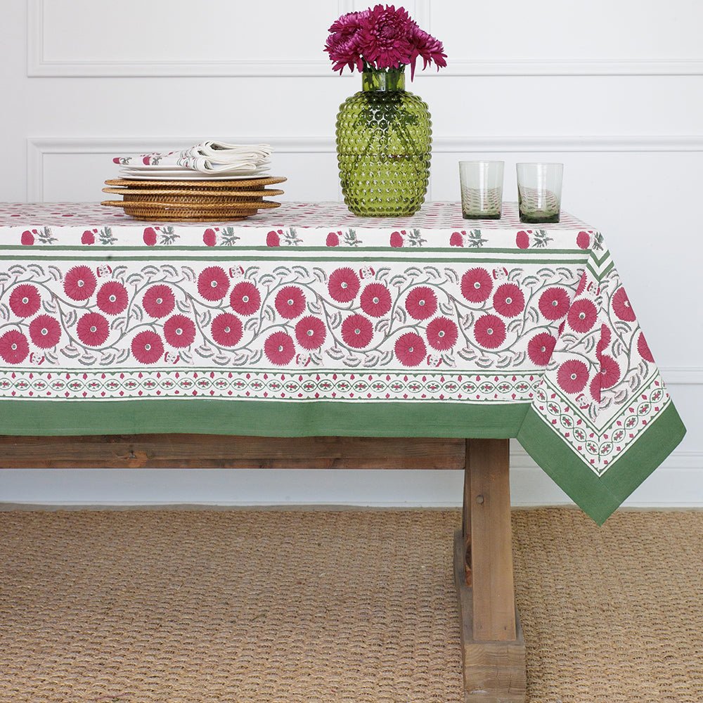 Tablecloth with floral pattern on a wooden table against a white wall.