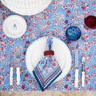 Table setting with floral tablecloth, plates, cutlery, and napkin on a wooden table.