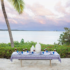Dining table set for dinner with a scenic ocean view and palm tree.