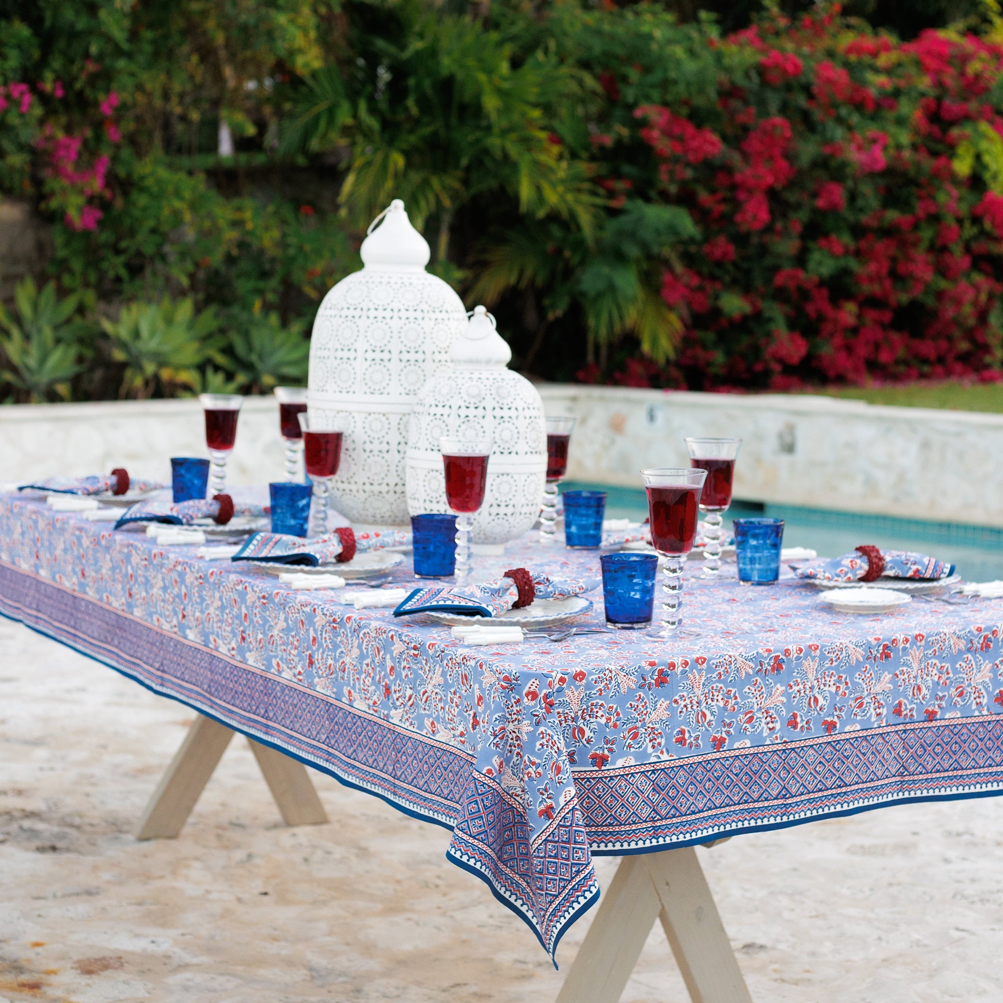 Dining table set with a floral tablecloth set outdoors.