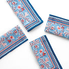 Set of four blue napkins with red and white floral patterns on a white background