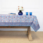 Tablecloth with floral pattern on a wooden table against a white wall.