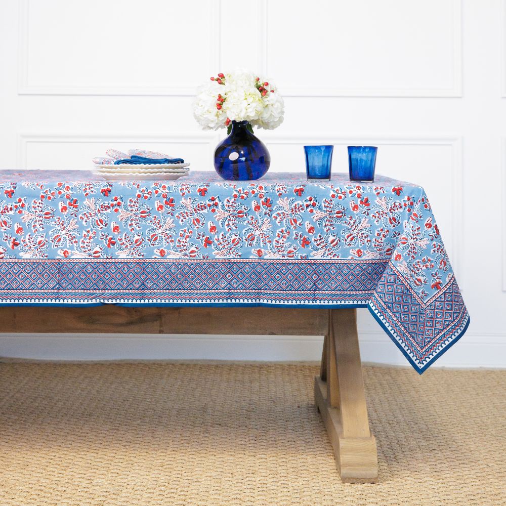Tablecloth with floral pattern on a wooden table against a white wall.