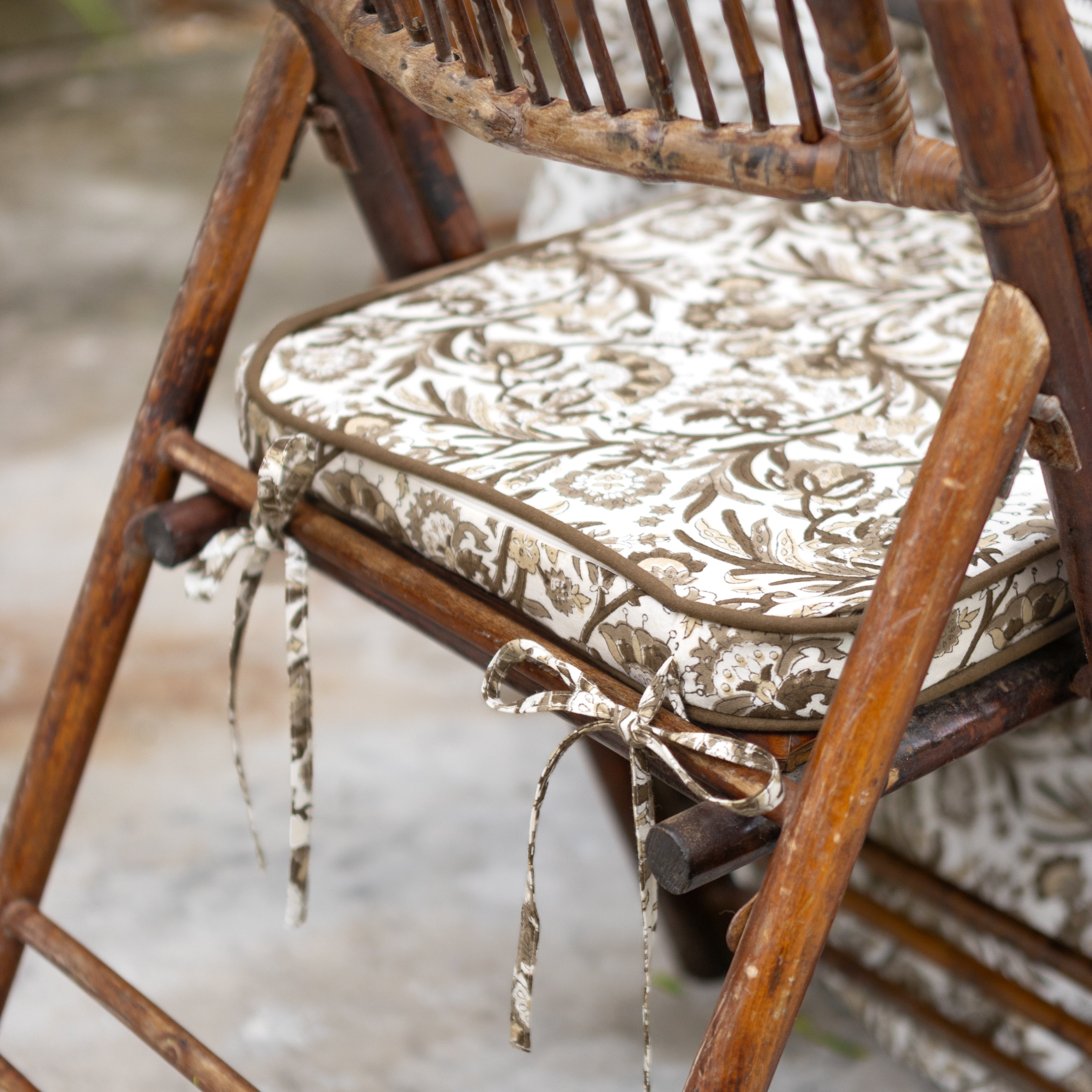 Wooden chair with a patterned cushion and decorative ribbon on a blurred background