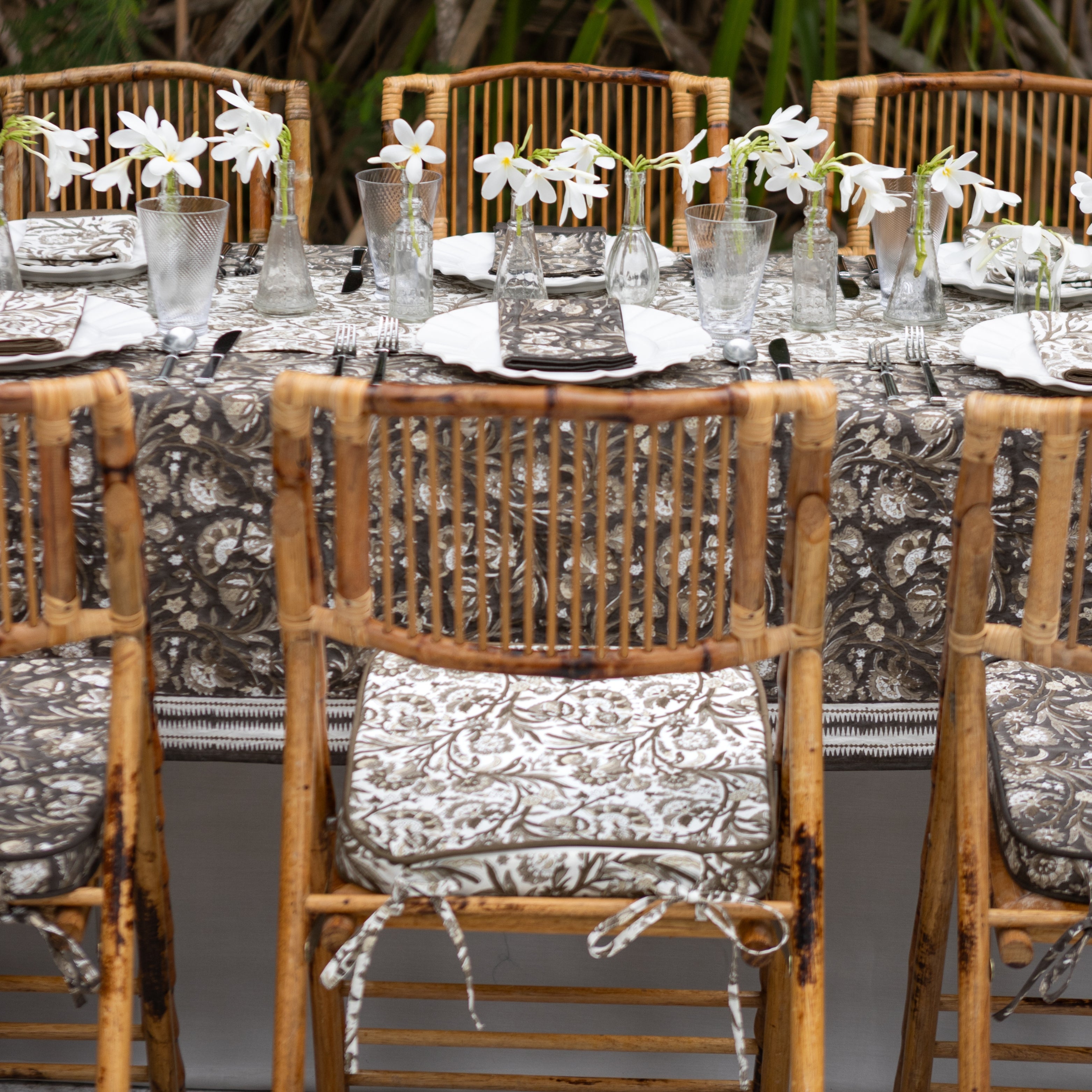 Dining table set with chairs and floral centerpieces in an outdoor setting