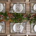 Elegant table setting with decorative plates, silverware, and candles on a wooden surface.