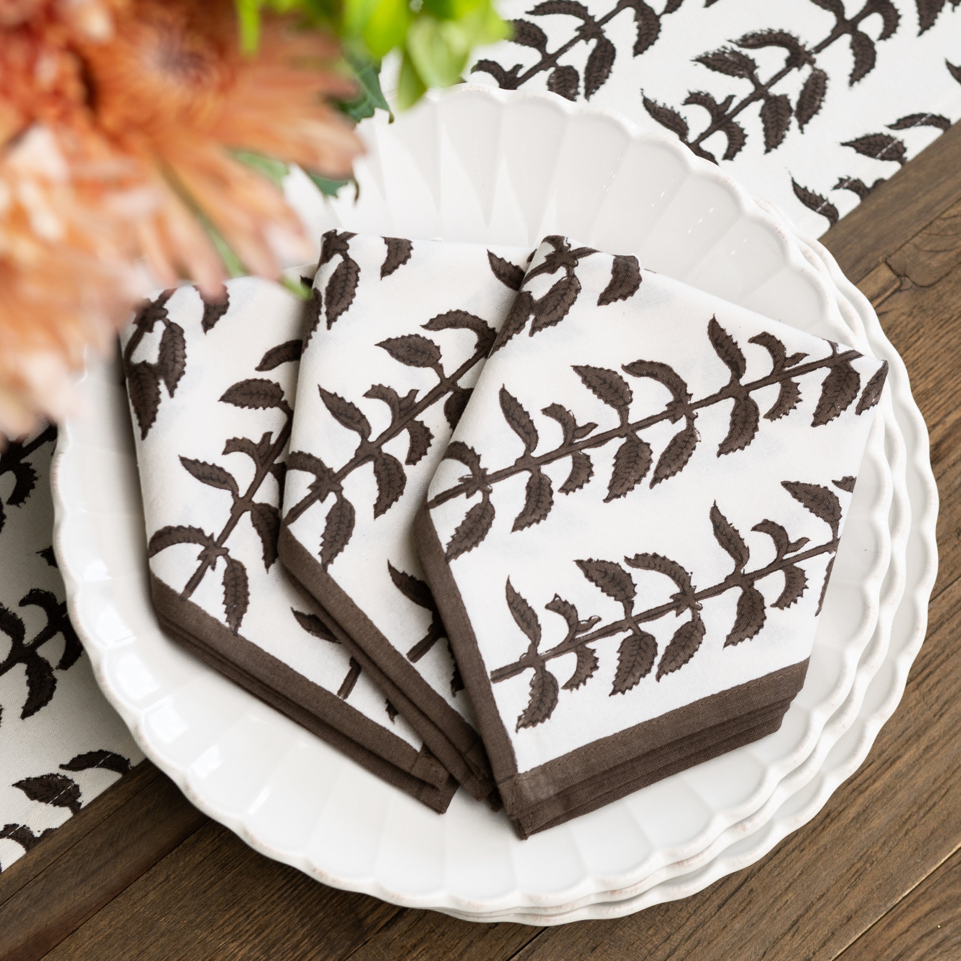 White napkins with brown leaf pattern on a white plate