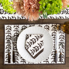 Dining table setting with white plates, cutlery, and a decorative napkin on a brown and white patterned placemat.