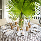 Dining table set with a tropical leaf decoration in a bright room.