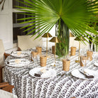 Dining table set with a patterned tablecloth, wicker accents, and decorative elements.
